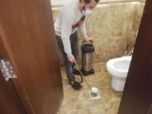 أحد فنيين رش الحشرات يرش المبيدات داخل البلوعات